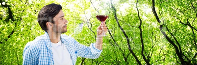 Man tasting wine against forest