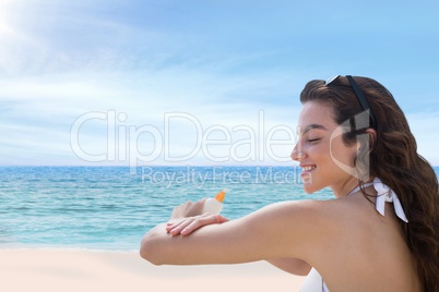 Happy woman at the beach putting on cream