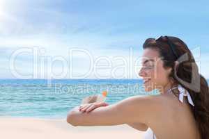 Happy woman at the beach putting on cream