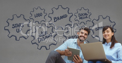 Happy business people holding a tablet and a computer against grey background with graphics