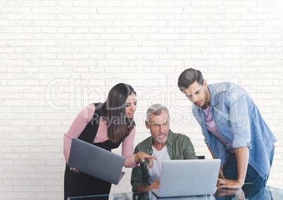Business people at a desk looking at a computer against white wall