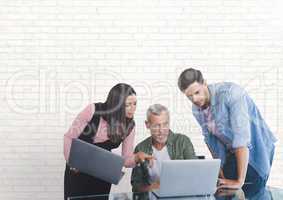 Business people at a desk looking at a computer against white wall