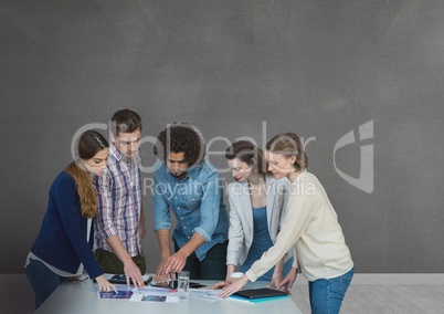 Business people at a desk looking at a computer against grey background