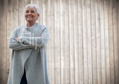 Elderly woman arms folded against blurry wood panel