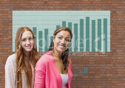 Happy business women standing against brick wall with graphics