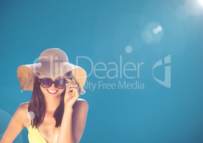 Millennial woman looking through sunglasses against blue background and flare