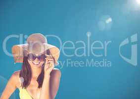 Millennial woman looking through sunglasses against blue background and flare