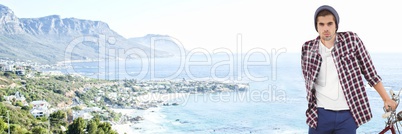 Millennial man with bicycle against blurry coastline