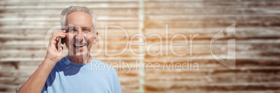 Elderly man on phone against blurry wood panel