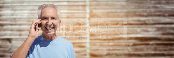 Elderly man on phone against blurry wood panel