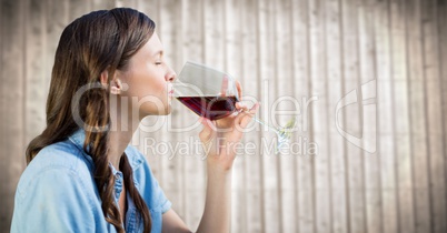 Woman tasting wine against blurry wood panel