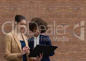 Happy business woman using a tablet against brick wall