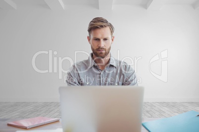 Business man at a desk using a computer against white wall