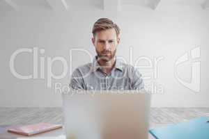 Business man at a desk using a computer against white wall