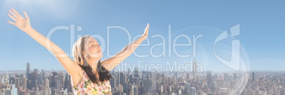 Millennial woman with arms out against skyline and Summer sky with flare