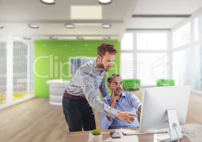 Business men at a desk pointing at a computer