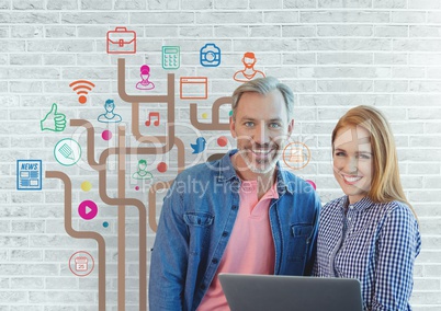 Happy business people holding a computer against white wall with graphics