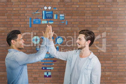 Happy business men doing a high five against brick wall with graphics