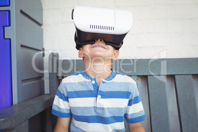 Boy watching virtual reality glasses while sitting on bench
