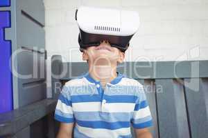 Boy watching virtual reality glasses while sitting on bench