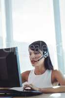 Businesswoman talking on headset while working at call center