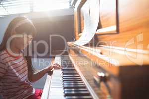 Smiling girl practicing piano in class