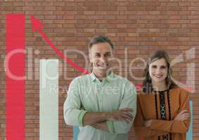 Happy business people standing against brick wall with graphics