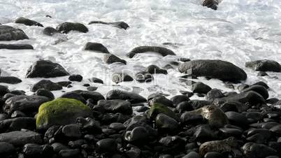 Waves folding down on stones on a beach
