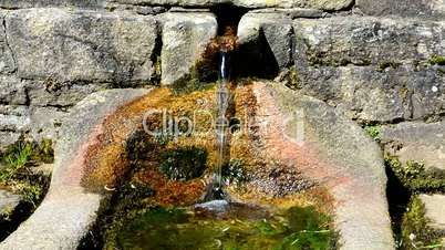 Stream of water coming out of a stone fountain, in a rural village