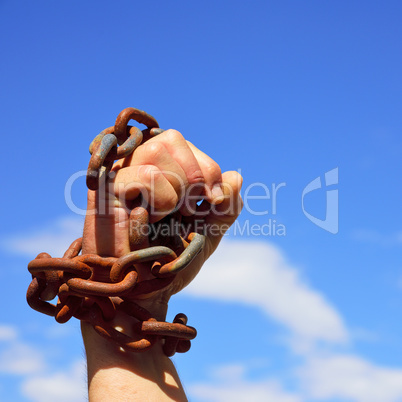 Man's hand is chained in iron chains