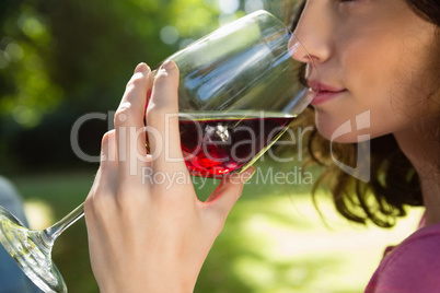 Woman drinking glass of red wine in park