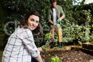 Smiling woman holding sapling plant in garden