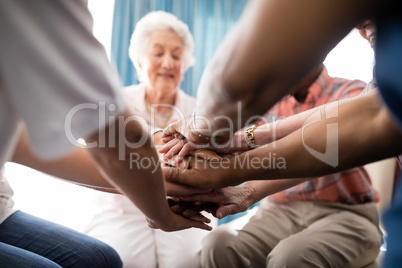 Cropped image of female doctor and senior people stacking hands