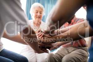 Cropped image of female doctor and senior people stacking hands