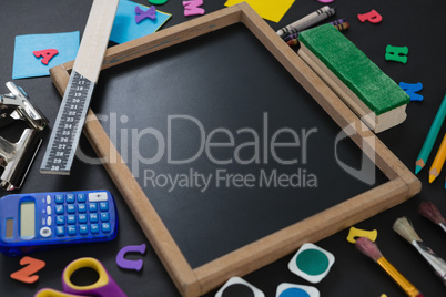 Blank slate surrounded by various school supplies