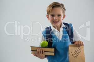 Smiling schoolboy holding books and lunch paper bag