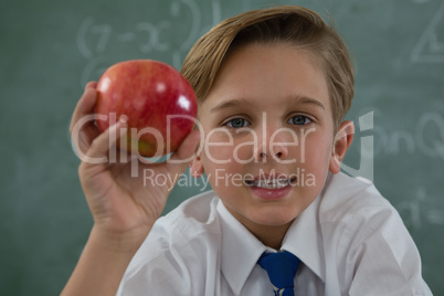 Schoolboy holding red apple against chalkboard Schoolboy holding red apple against chalkboard