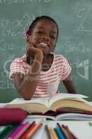 Schoolgirl reading book in classroom