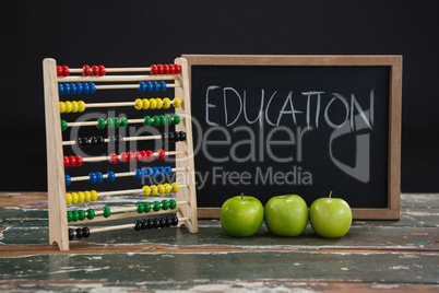 Education text on chalkboard with abacus and green apples