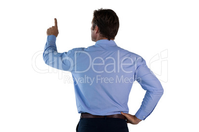 Rear view of businessman with hand on hip touching invisible interface