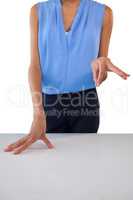 Mid section of businesswoman holding something while gesturing at table