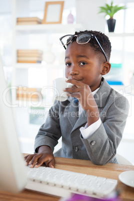 Businessman having coffee while using computer at desk