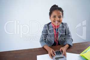 Portrait of happy girl pretending as businesswoman using calculator