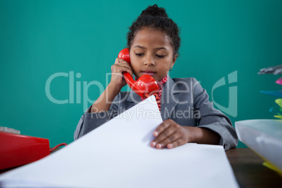 Businesswoman checking file while talking on land line