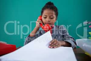 Businesswoman checking file while talking on land line