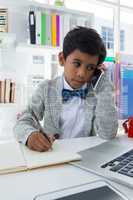 Businessman looking at laptop while talking on mobile phone