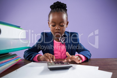 Serious businesswoman using calculator at desk