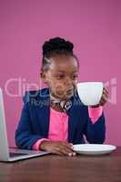 Businesswoman with laptop making face and drinking coffee