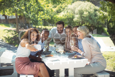 Friends taking selfie on mobile phone while having meal
