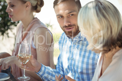 Happy friends interacting while having glass of wine